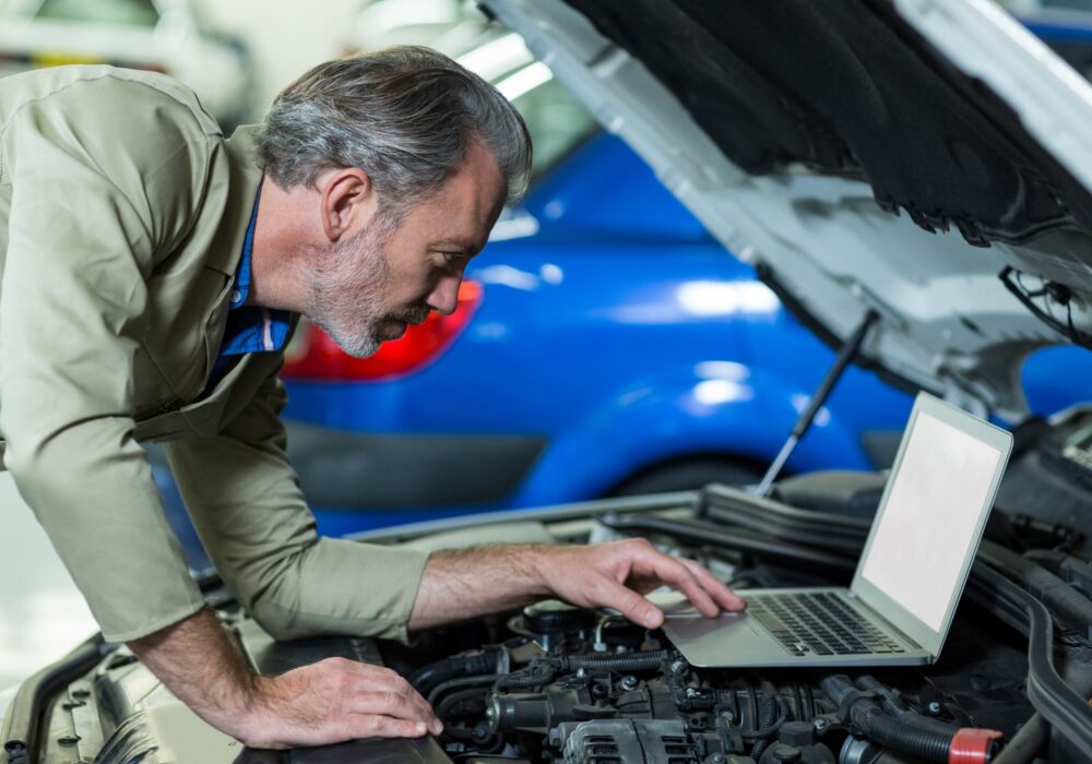 mechanic-using-laptop-while-servicing-car-engine